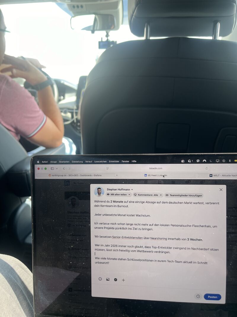 Ein Laptop ist im Vordergrund geöffnet und zeigt einen Entwurf für einen LinkedIn-Post von Stephan Hoffmann auf Deutsch. Im Hintergrund sieht man das Innere eines Autos, in dem eine Person auf dem Beifahrersitz sitzt.